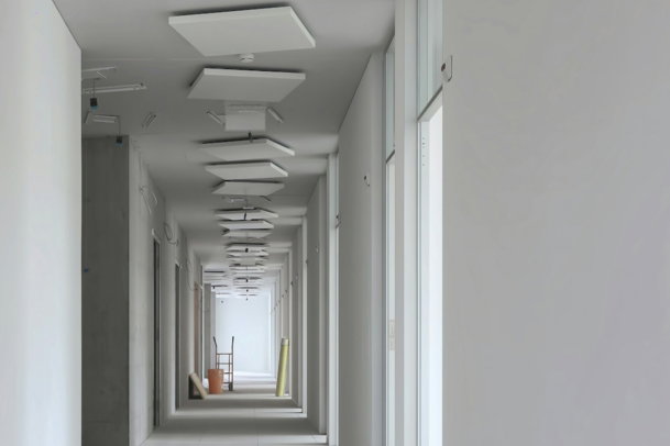 a long hallway with white walls and ceiling lights